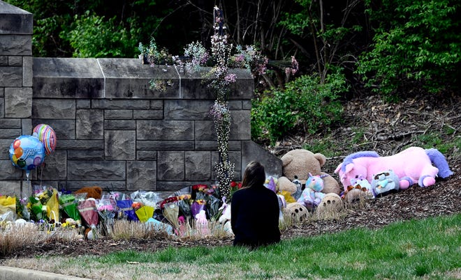 A woman sits in front of the makeshift memorial at the entrance to the Covenant School Tuesday, March 28, 2023, in Nashville, Tenn. Three children and three school staff members were killed by a former student in Monday’s mass shooting.