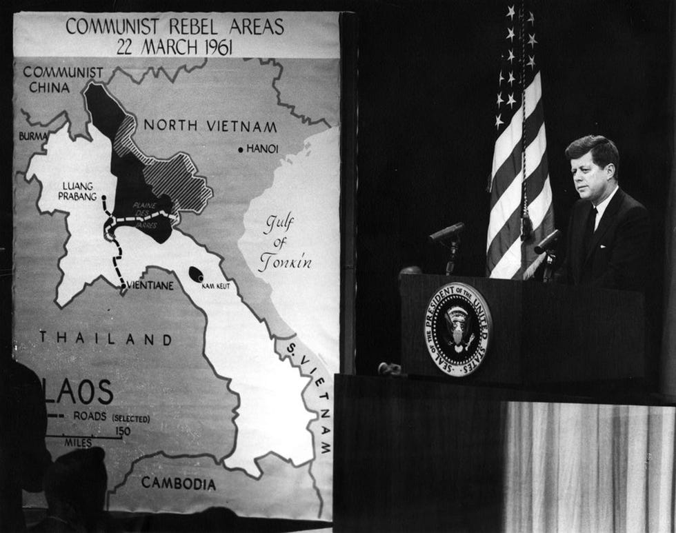 This photograph shows President John F. Kennedy standing at a lectern in the State Department auditorium in Washington, DC. A map of Laos on the left reads "Communist Rebel Areas, 22 March 1961."