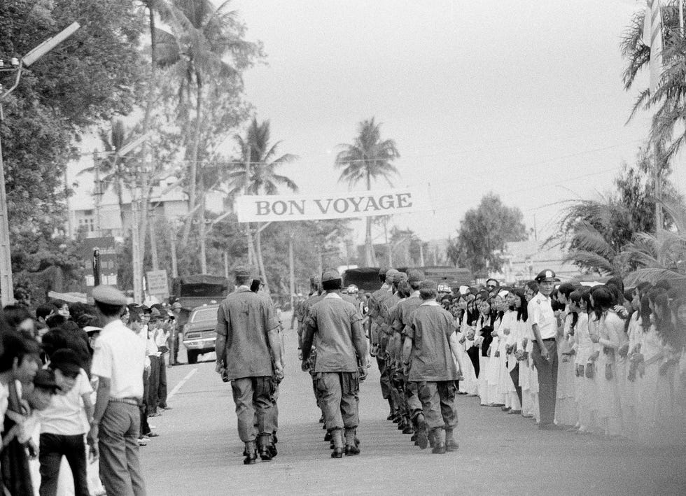 A bon voyage banner stretches overhead in Da Nang, South Vietnam, as soldiers march down a street following a farewell ceremony for some of the last U.S. troops in the country's northern military region, March 26, 1973.