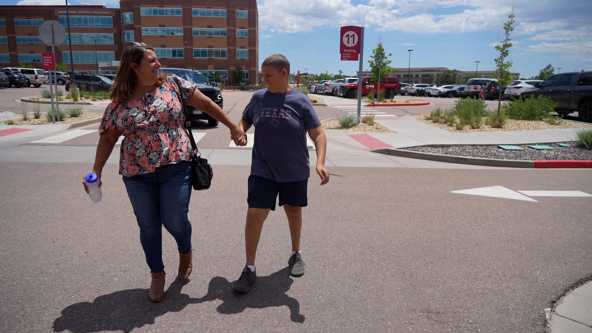 Screen capture from Shift: The RAGBRAI Documentary: Torie Giffin holds her son Daniel's hand as they walk up to Children's Hospital Colorado for an appointment in July 2022, in Colorado Springs. 