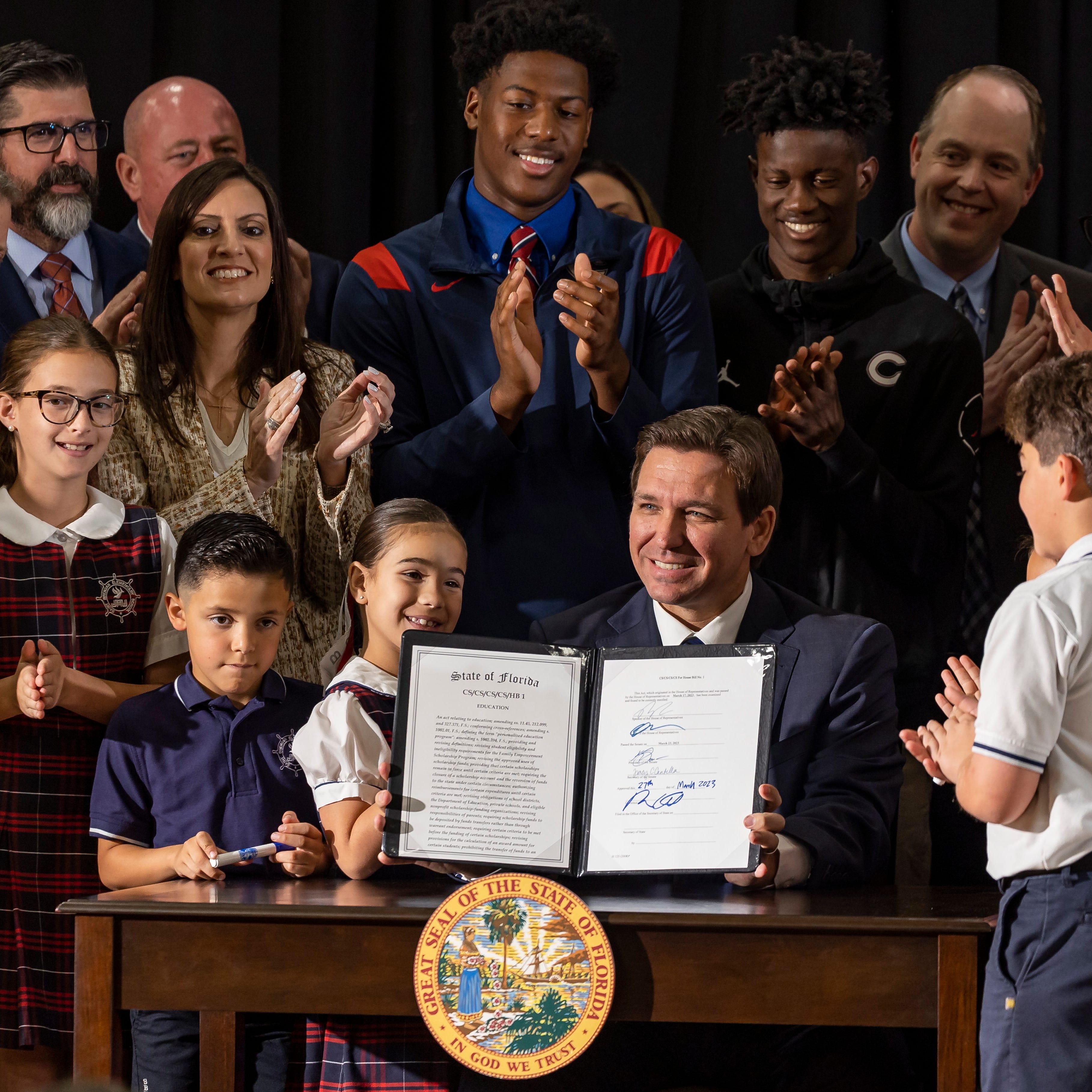 Florida Gov. Ron DeSantis signs a bill to expand school vouchers statewide on March 27, 2023, in Miami.