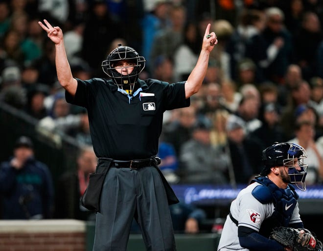 Home plate umpire Mark Carlson updates the count on Seattle Mariners' J.P. Crawford after Cleveland Guardians relief pitcher James Karinchak was called for a pitch-clock violation in the eighth inning of an opening day baseball game Thursday, March 30, 2023, in Seattle. (AP Photo/Lindsey Wasson)