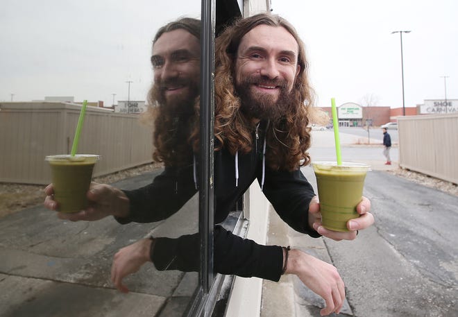 Clayton Farms Salads restaurant co-founder Clayton Mooney serves a Sweet Matcha smoothie through the drive-thru window of the restaurant on Grand Avenue in Ames.