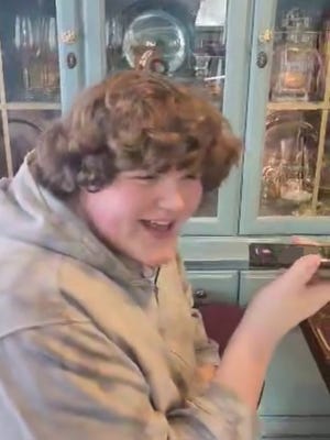 Eric Kilburn Jr. listens to Shaquille O'Neal on speaker phone at his home in Goodrich on March 29, 2023. O'Neal reached out to the family after hearing about their struggle to find Eric size 23 shoes.