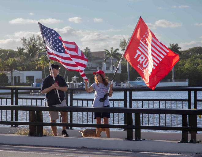 Trump supporters hold flags near Mar-a-Lago the day after a New York City grand jury voted to indict the former U.S. President March 31, 2023.