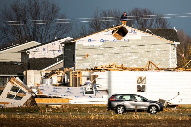 A person walks on the roof of a building damaged in a storm after a tornado warning in Johnson County, Friday, March 31, 2023, in Hills, Iowa. (Joseph Cress/Iowa City Press-Citizen via AP)