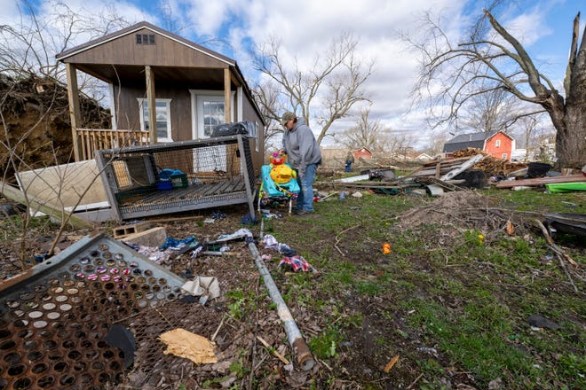 Misty Grimes, searches through debris scattered throughout her yard left from a late-night tornado in Sullivan, Ind., Saturday, April 1, 2023. Grimes and her husband, Matt, were home as the storm hit, and found shelter inside their home. Neither were injured. (AP Photo/Doug McSchooler)