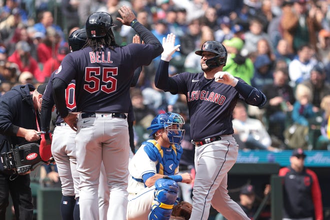 Cleveland Guardians catcher Mike Zunino, right, celebrates at home plate after hitting a home run scoring Josh Bell (55) and Andres Gimenez as Seattle Mariners catcher Cal Raleigh looks on during the second inning of a baseball game, Sunday, April 2, 2023, in Seattle. (AP Photo/Jason Redmond)