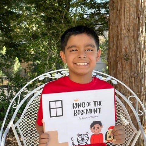 Akshay Varma, 10, poses with the book he helped create, 'King of the Basement,' which is based on his experience with long COVID.