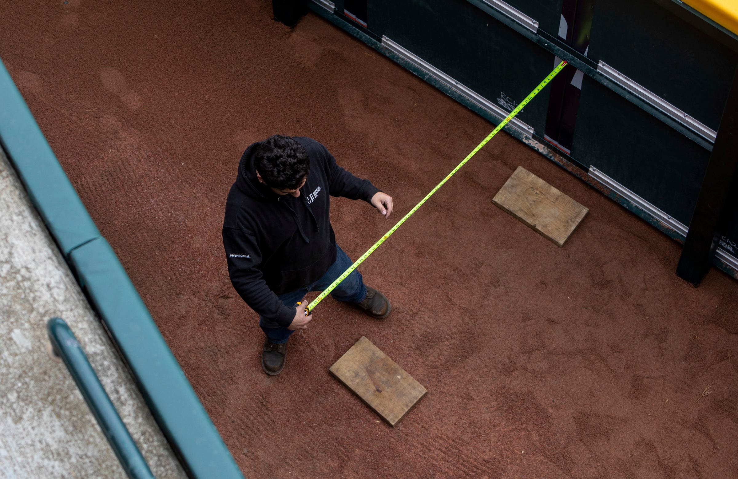 Michael Pate measures an area for a stage he will build behind the outfield wall in Comerica Park during Opening Day preparations on Wednesday, April 5, 2023.