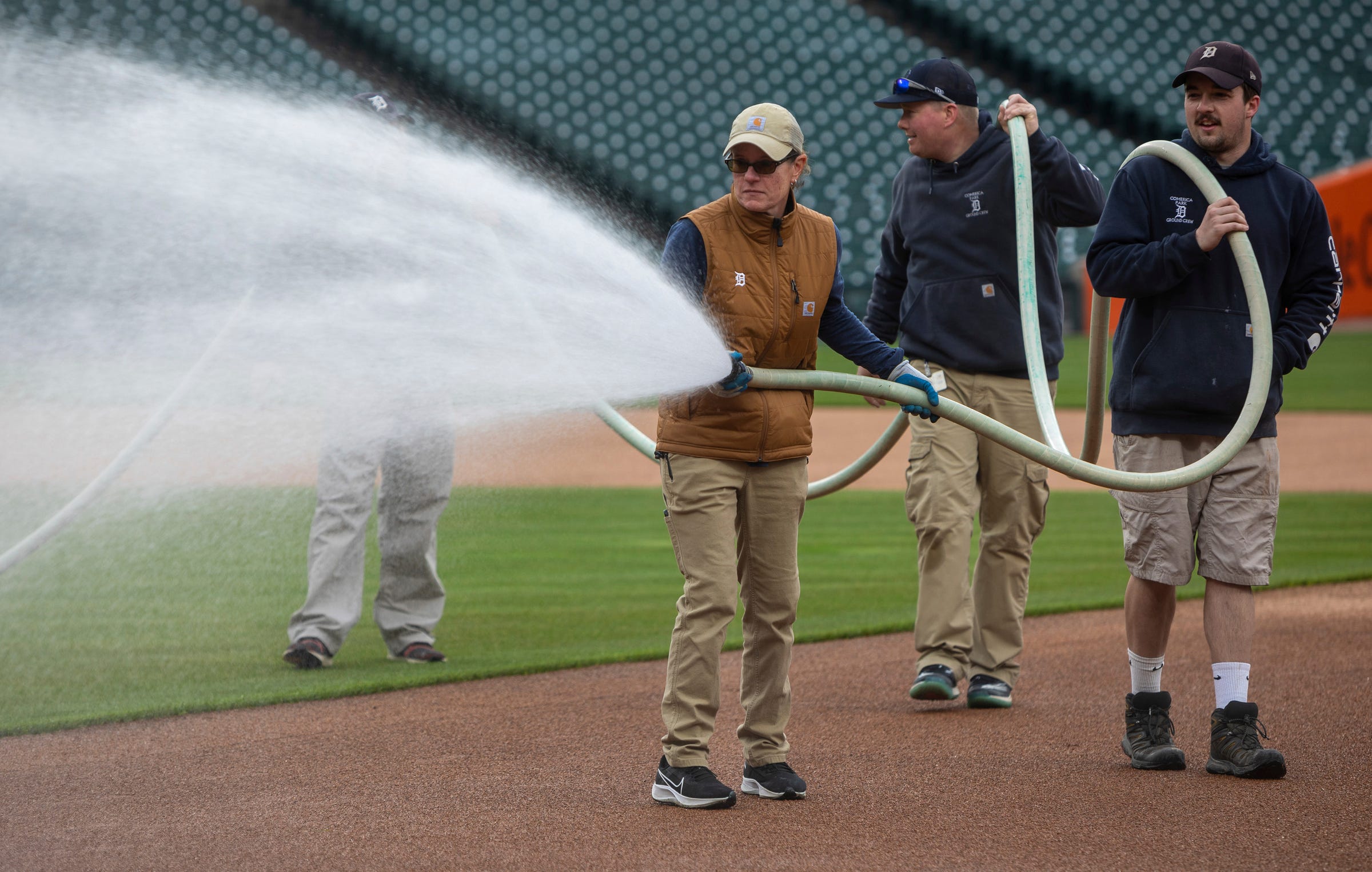 Heather Nabozny, the head groundkeeper for the Detroit Tigers, waters the "skin," which refers to the infield soil, with members of her ground crew during the Detroit Tigers' Opening Day at Comerica Park in Detroit on Thursday, April 6, 2023.