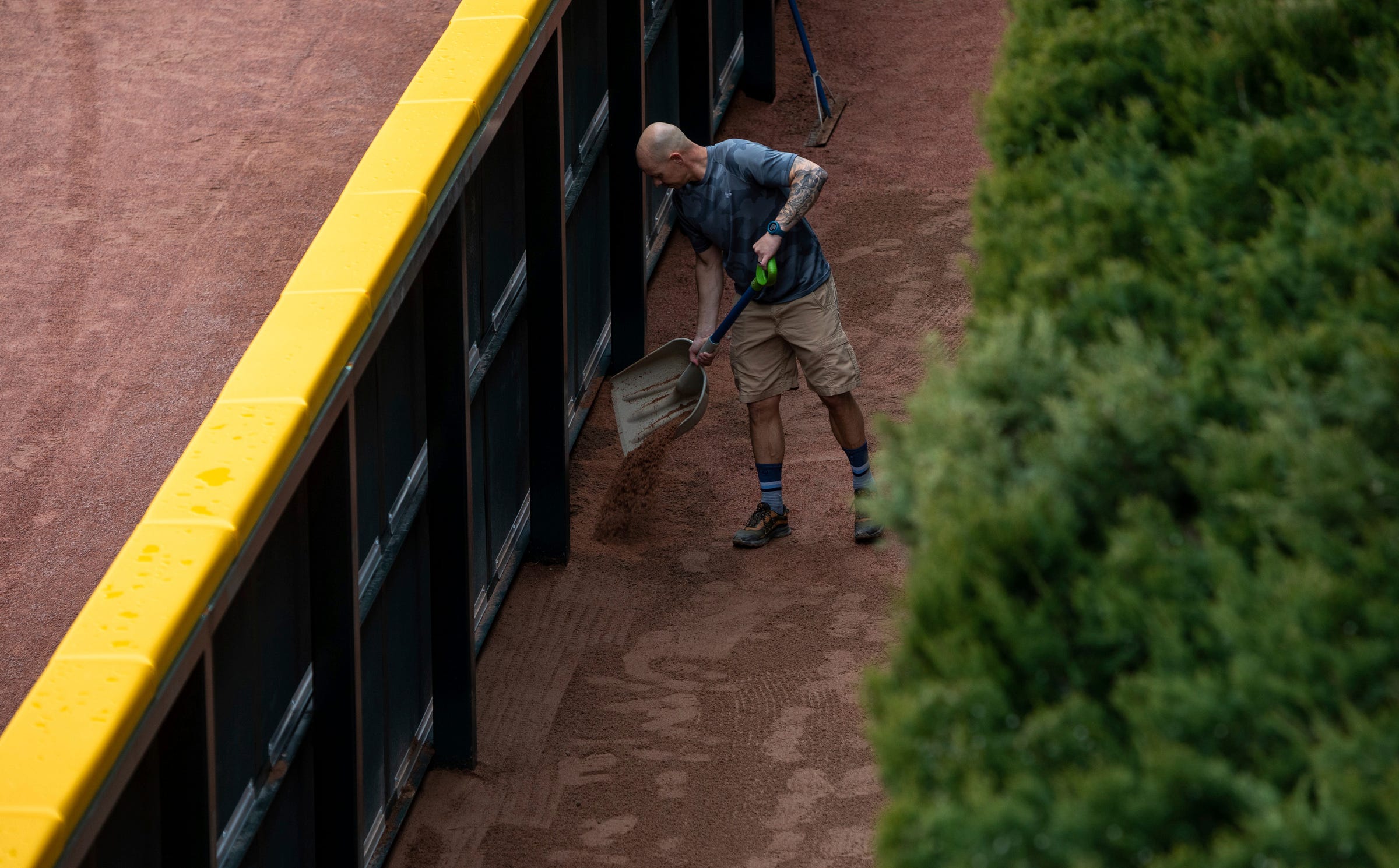 A member of the grounds crew uses a shovel to pour dirt behind the outfield walls of Comerica Park during Opening Day preparations on Wednesday, April 5, 2023.