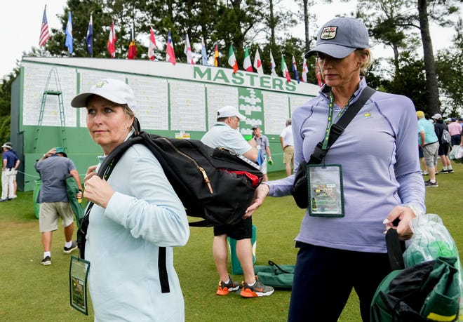 April 7, 2023; Augusta, Georgia, USA; Judy Streiff (right) holds Sylvia Martin's backpack near the Masters scoreboard during the second round of The Masters golf tournament. The two, both from Frisco, Texas, were sitting near the 17th tee under an awning to protect from falling pinecones when several trees were uprooted and fell onto the ground where they were sitting. There was a loud crack and a man sitting near them, Deshey Thomas, of Fuquay-Varina, NC, shouted for everyone to move to safety. The group crossed the rope to the 17th hole to avoid falling trees. Martin's bag was torn apart, and Streiff's chair was one of many that got crushed. Mandatory credit: Rob Schumacher-USA TODAY Network