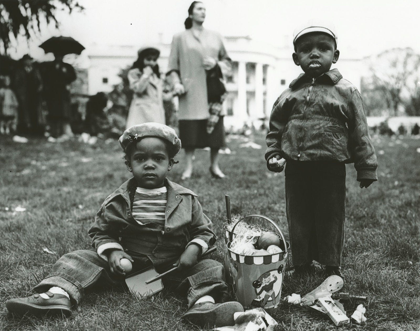 In this photograph taken by National Park Service Photographer Abbie Rowe on April 6, 1953, two young children enjoy treats from the their Easter basket at the annual White House Easter Egg Roll.
