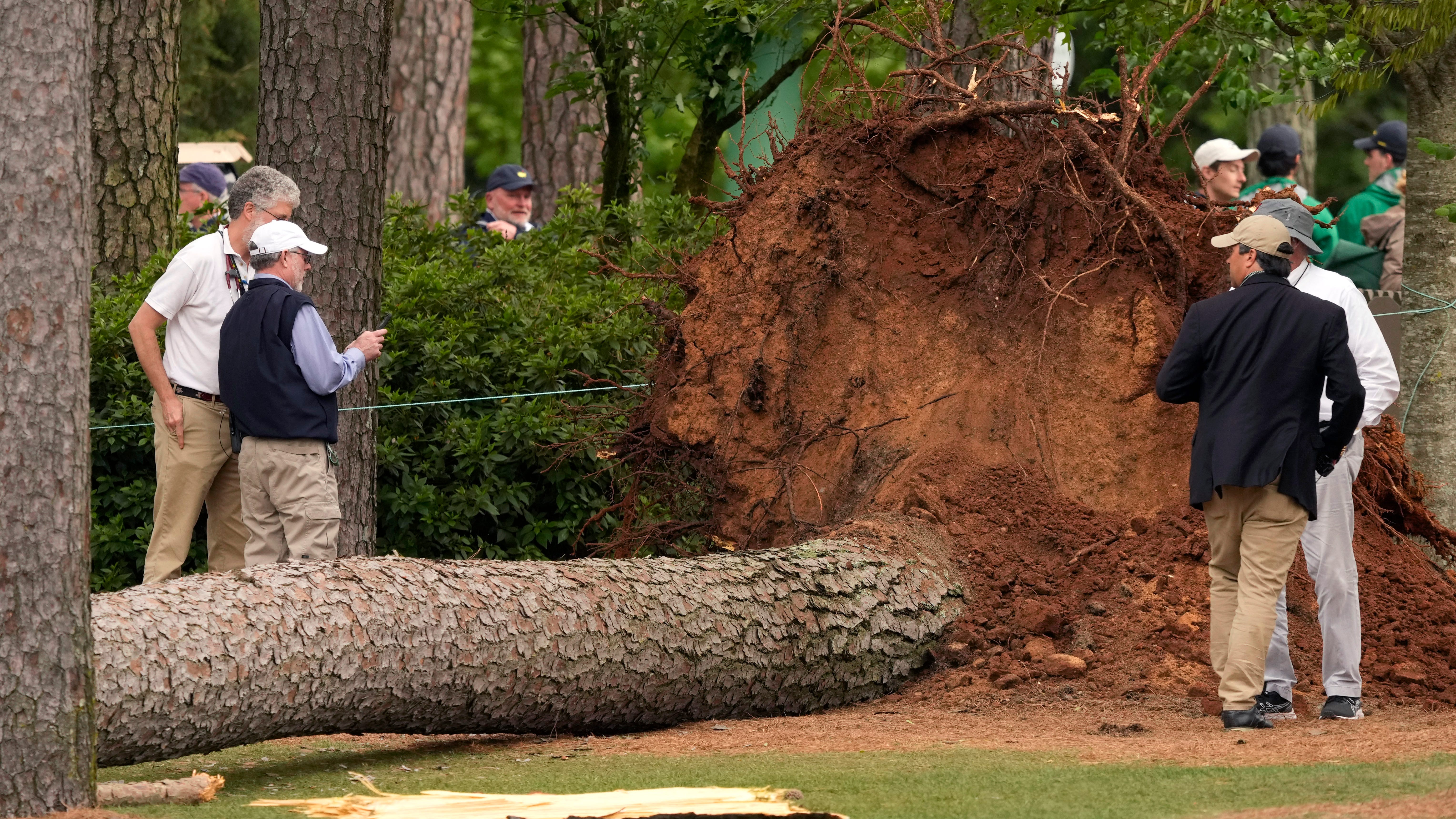 Volunteers and staff secure the area where a tree fell Friday near the 17th tee at the Masters.