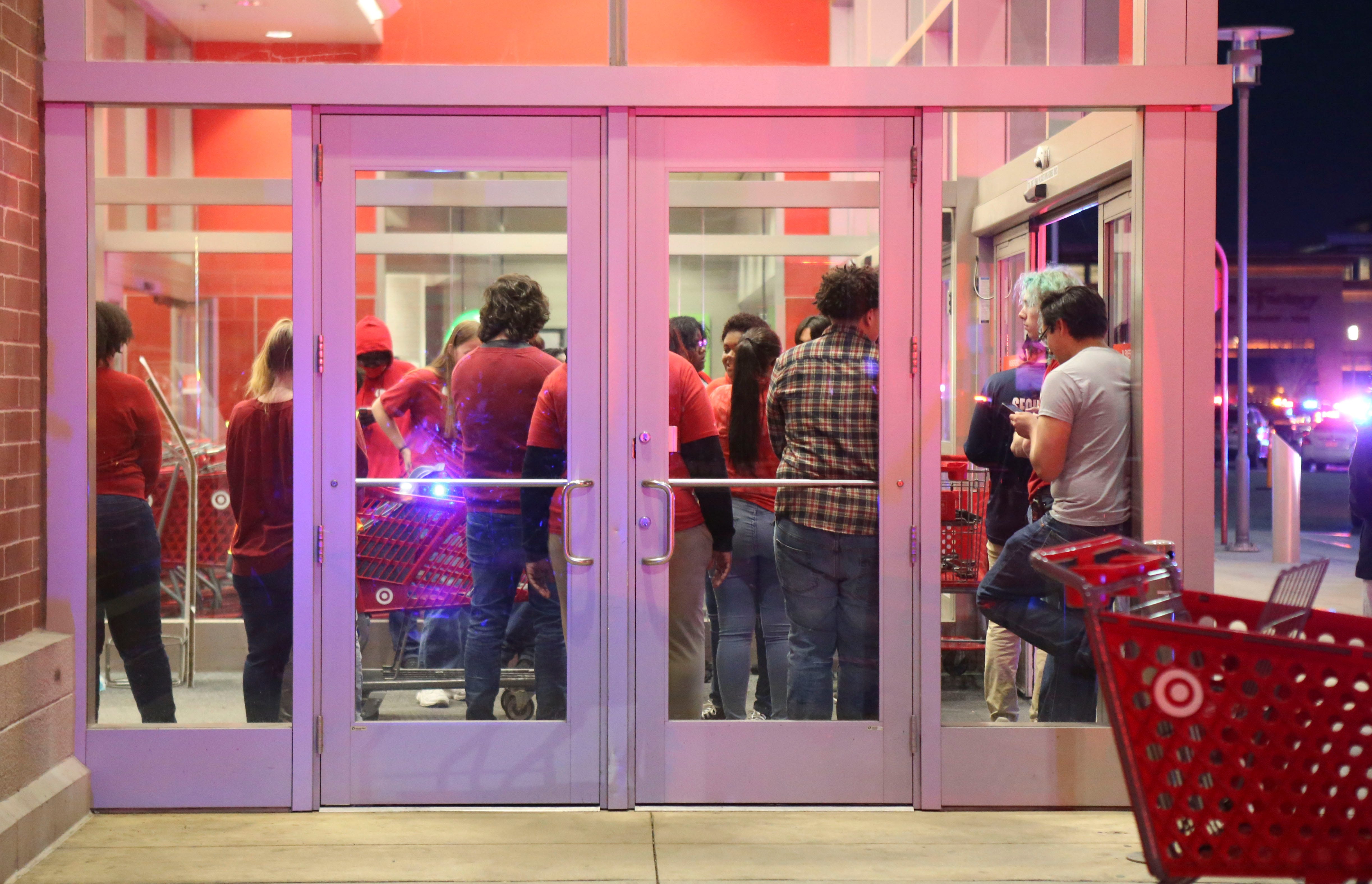 Target employees gather at the store parking lot entrance as police, fire and medical personnel respond in force to the food court entrance at the Christiana Mall after a shooting Saturday evening, April 8, 2023.