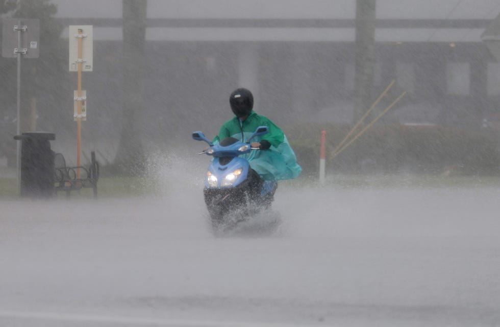 April 12, 2023: A person drives a scooter through a flooded street in Dania Beach, Florida. Heavy rain passed through the South Florida area causing some area flooding.