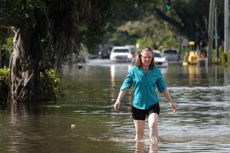 A woman wades through high flood waters in a Fort Lauderdale, Fla., neighborhood  on Thursday, April 13, 2023.