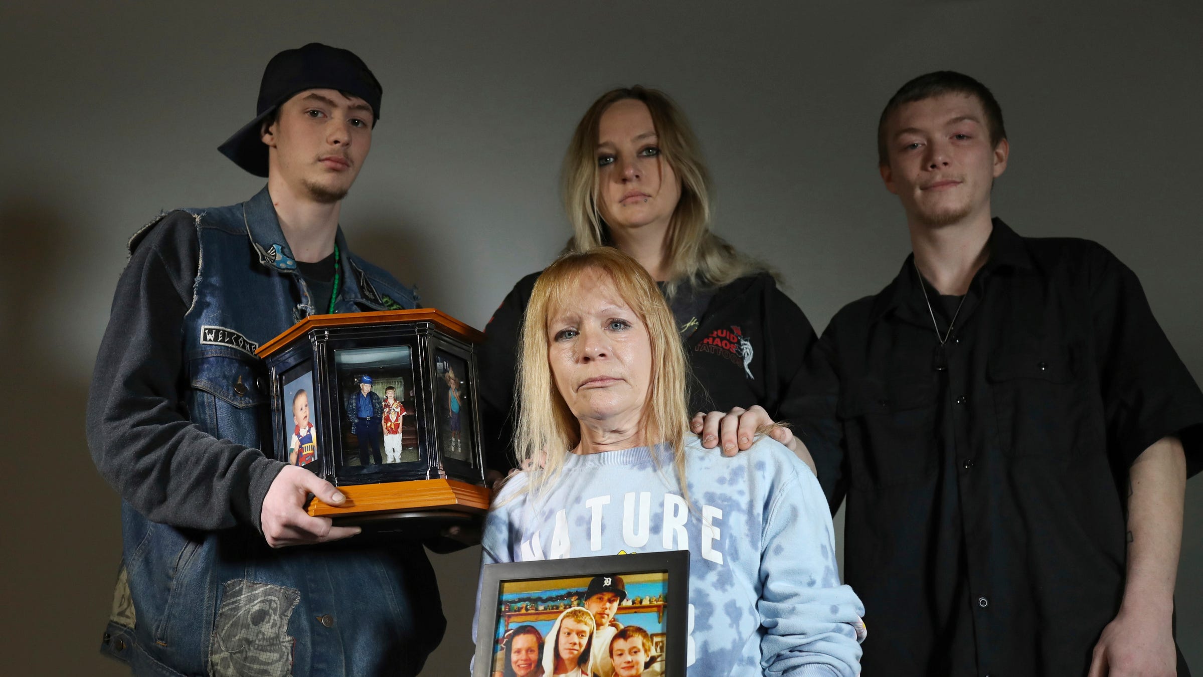 Cynthia Cooper, mother of Shane Cousins, holds a family photo as she poses with, Stone Cousins, 23,  Jessica Cooper, 34, and Shannon Cousins, 26, on Monday, April 3, 2023. Shane was shot and killed by Michigan State Police officers after he shot at a police helicopter.