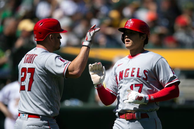 Los Angeles Angels' Mike Trout (27) greets teammate Shohei Ohtani after they scored against the Oakland Athletics during the third inning on Saturday, April 1, 2023, in Oakland, Calif. (AP Photo/D. Ross Cameron)