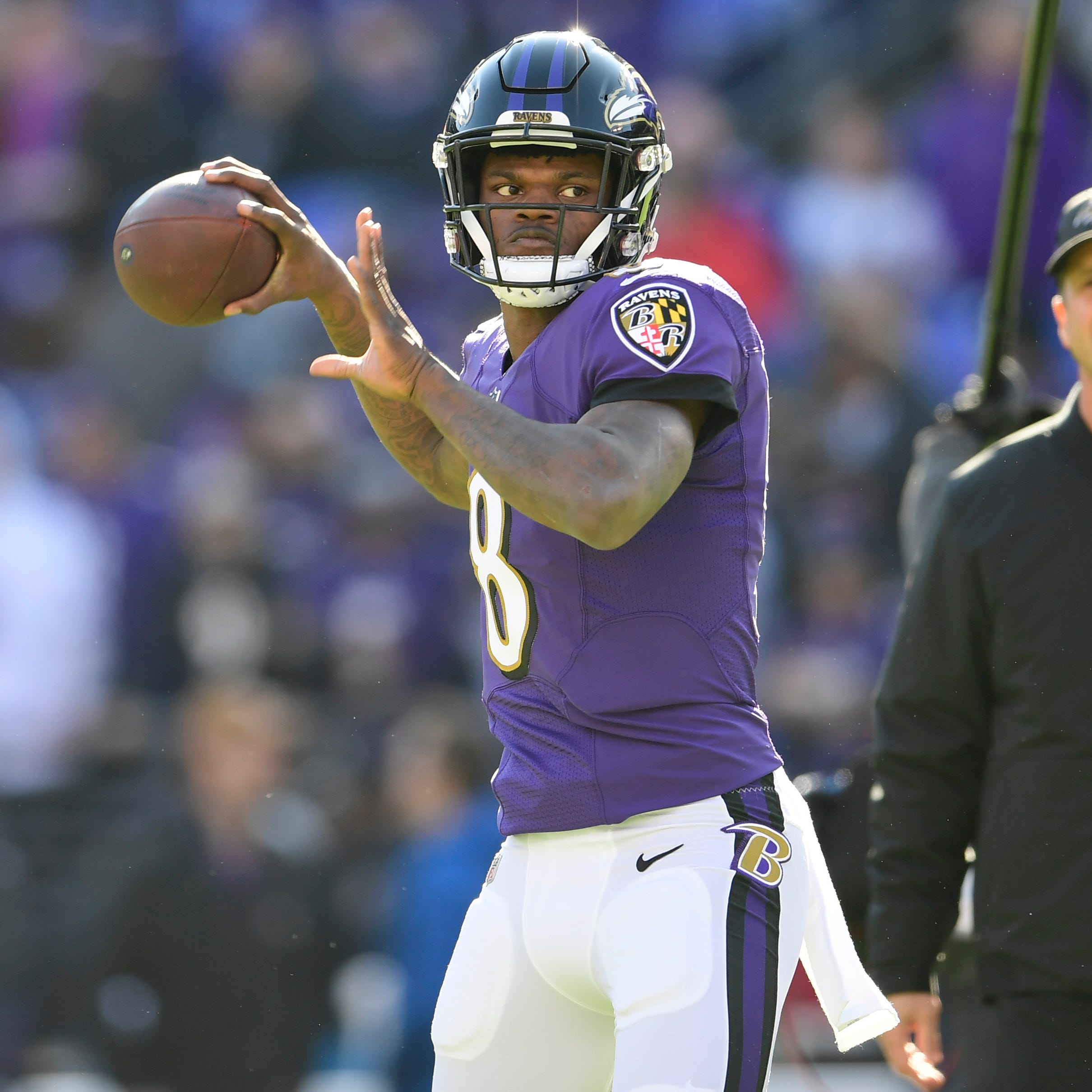 Baltimore Ravens quarterback Lamar Jackson (8) passes as head coach John Harbaugh looks prior to the game against the Los Angeles Chargers in a AFC Wild Card playoff football game at M&T Bank Stadium.