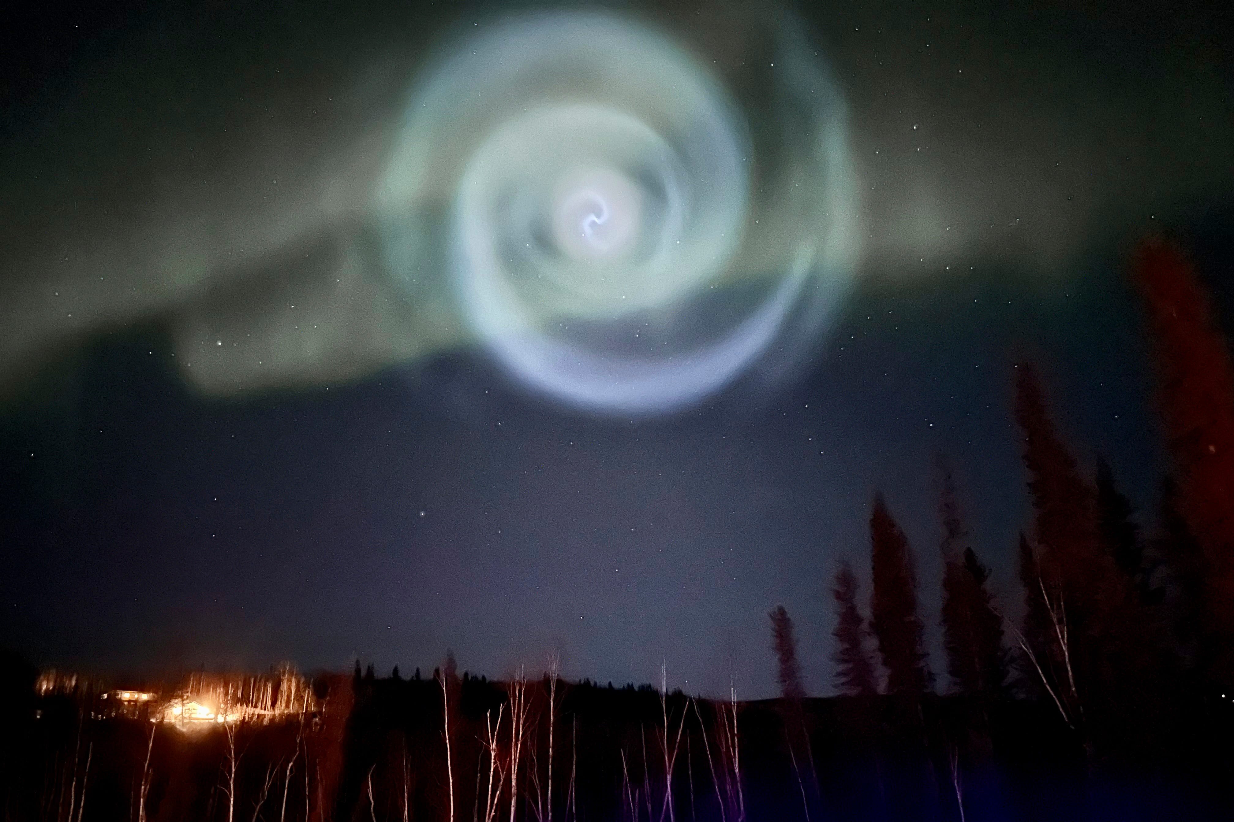A inexperienced spiral within the Alaskan night time sky amid aurora as a result of rocket gas