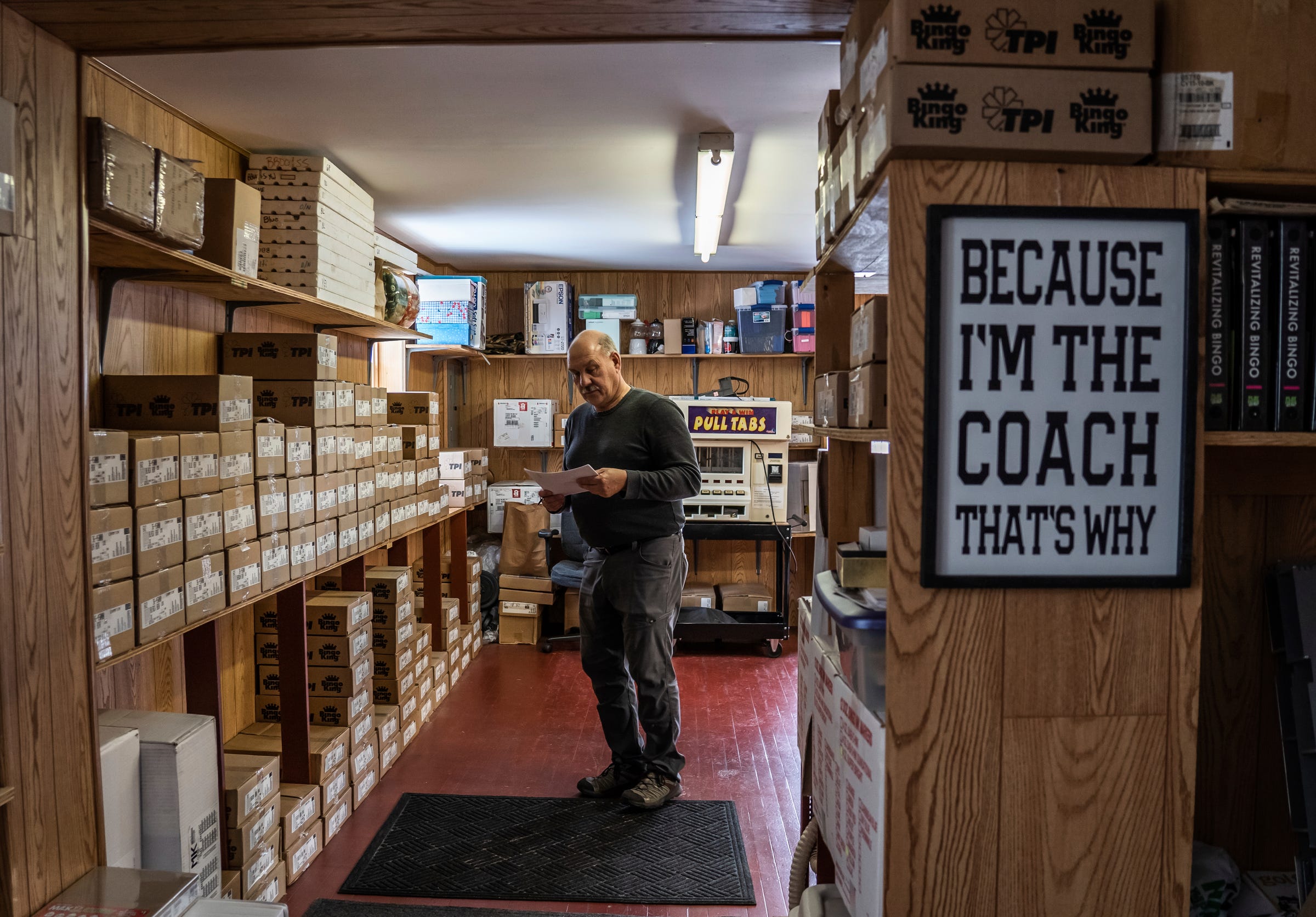 Higgins Bingo Supplies owner Jim Higgins, who spent years coaching the NMU women's hockey team, looks over an order for a client in the back room of his store in Marquette on Friday, Feb. 10, 2023. “I don’t know if it’ll ever come back the way it was,” he said. “I’ve got a Rolodex back there that’s loaded with all our closed accounts. Three-quarters of the bingos up here have shut down."