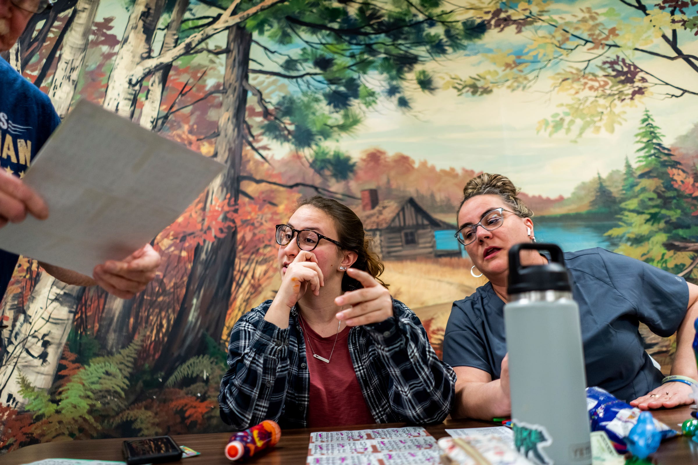 Brooke Letson, 41, right, looks on as her 22-year-old daughter, Taylor Letson, has her card checked for winnings by floor worker Steve Williams during bingo night at the Odd Fellows building in Ishpeming on Friday, Feb. 10, 2023, in Michigan's Upper Peninsula. “I like bingo because it costs me $30 to do this and you’re here for how many hours? Where if you’re gambling at the casino, $30 is gone in five minutes." Brooke Letson said. "This spreads that $30 out.”