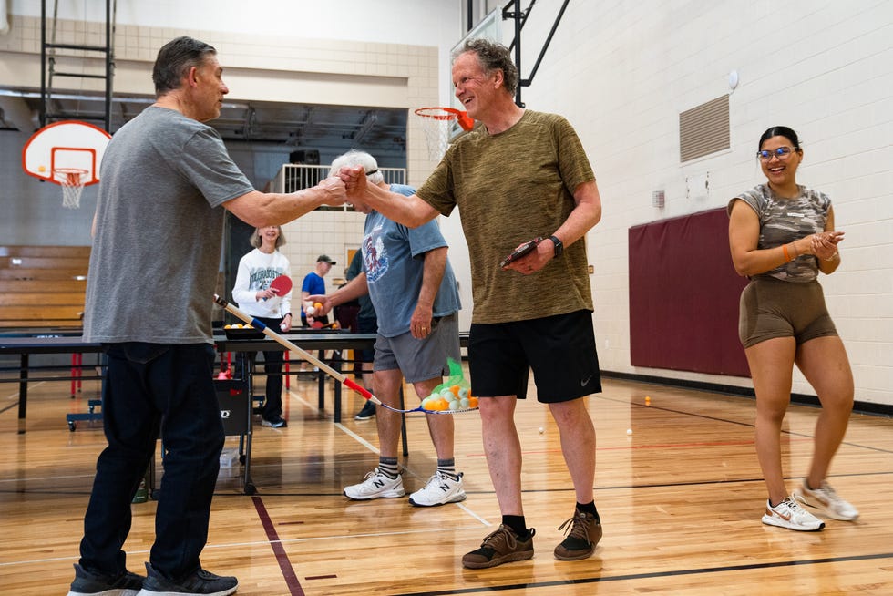 Gil Wette, center, receives knuckles on his birthday at a NeuroPong session on April 6, 2023. Participants say the program has a strong sense of community.