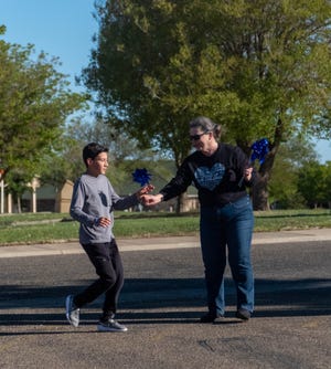 The first runner passes the finish line Saturday morning at the Bridge Children's Advocacy Center's "Walk A Mile in Their Shoes" walk/run in Amarillo.