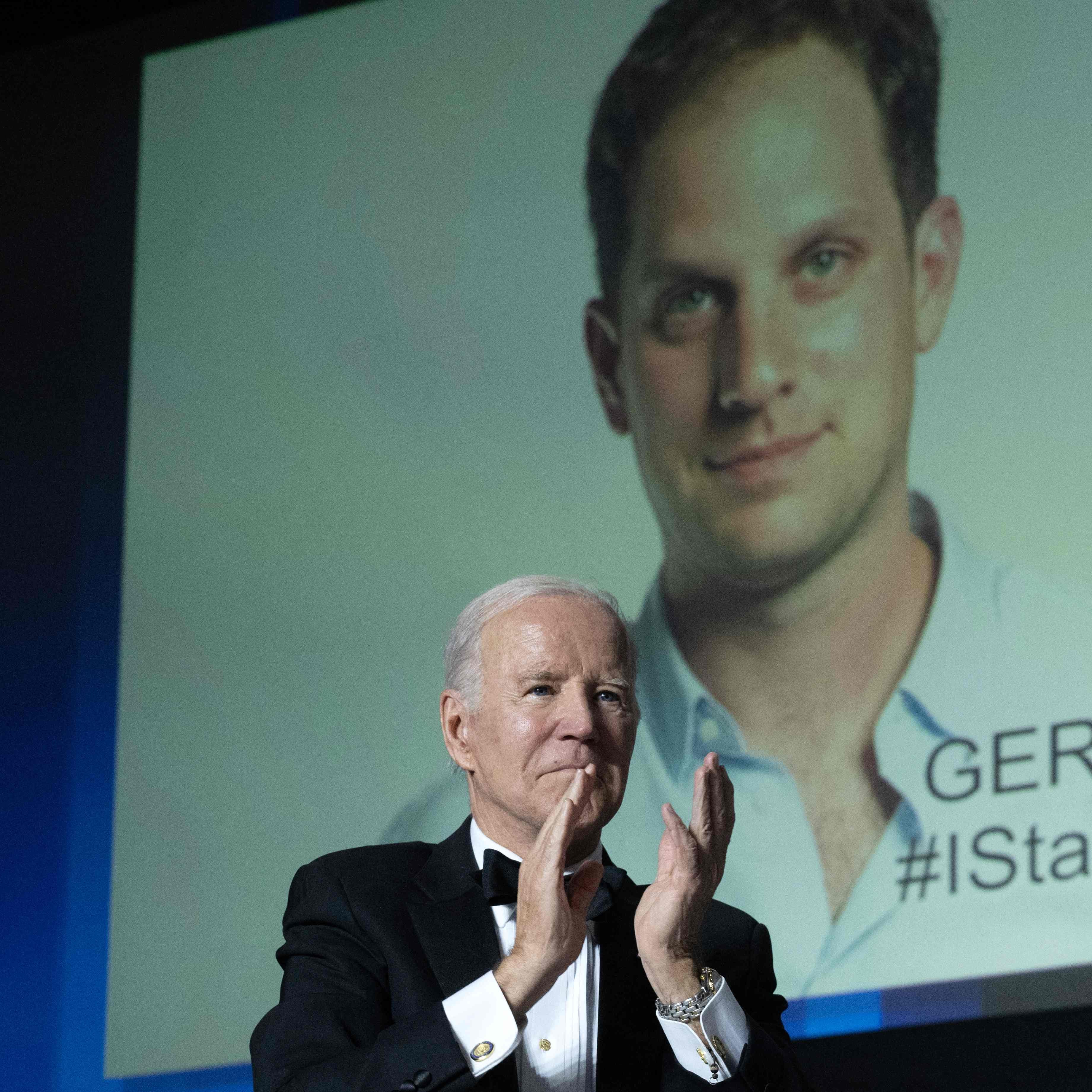 US President Joe Biden gestures as an image of US journalist Evan Gershkovich appears onscreen during the White House Correspondents' Association dinner at the Washington Hilton in Washington, DC, April 29, 2023. (Photo by SAUL LOEB/AFP via Getty Images)