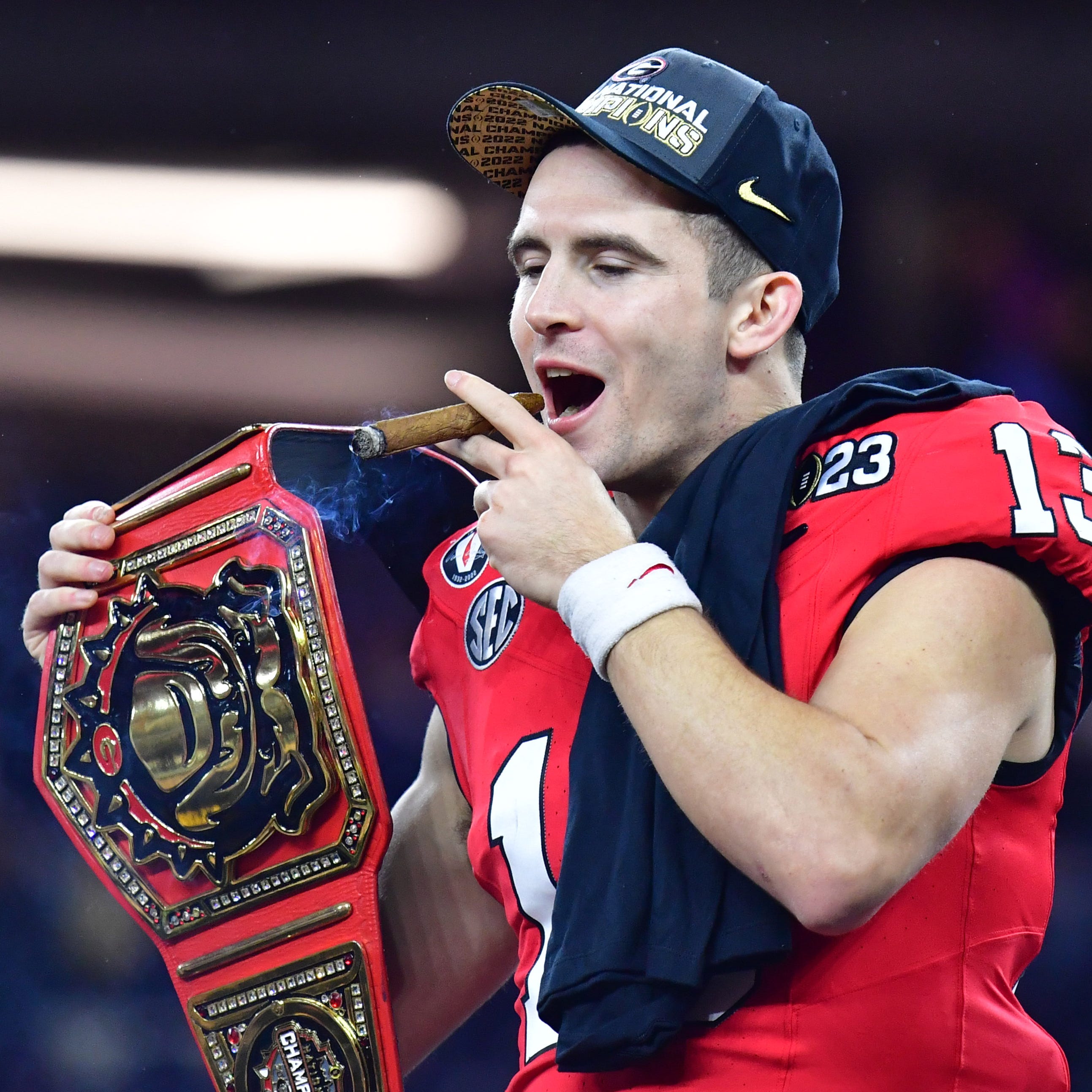 Georgia Bulldogs quarterback Stetson Bennett (13) celebrates with a cigar and championship belt after defeating the TCU Horned Frogs in the CFP national championship game at SoFi Stadium.