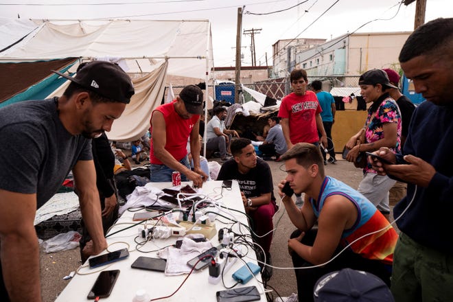 Migrants charge their phones at an impromptu encampment behind the Opportunity Center for the Homeless in El Paso, Texas on May 3, 2023. Hundreds of migrants are seeking refuge at the homeless center. 
