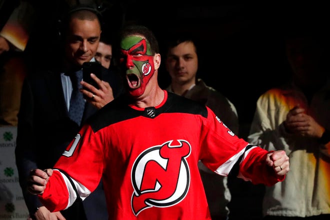 Actor Patrick Warburton, center, is dressed as Seinfeld cast member David Puddy, while walking up to center ice for the ceremonial puck drop prior to an NHL hockey game between the New Jersey Devils and the Pittsburgh Penguins, Tuesday, Feb. 19, 2019, in Newark, N.J. (AP Photo/Julio Cortez)