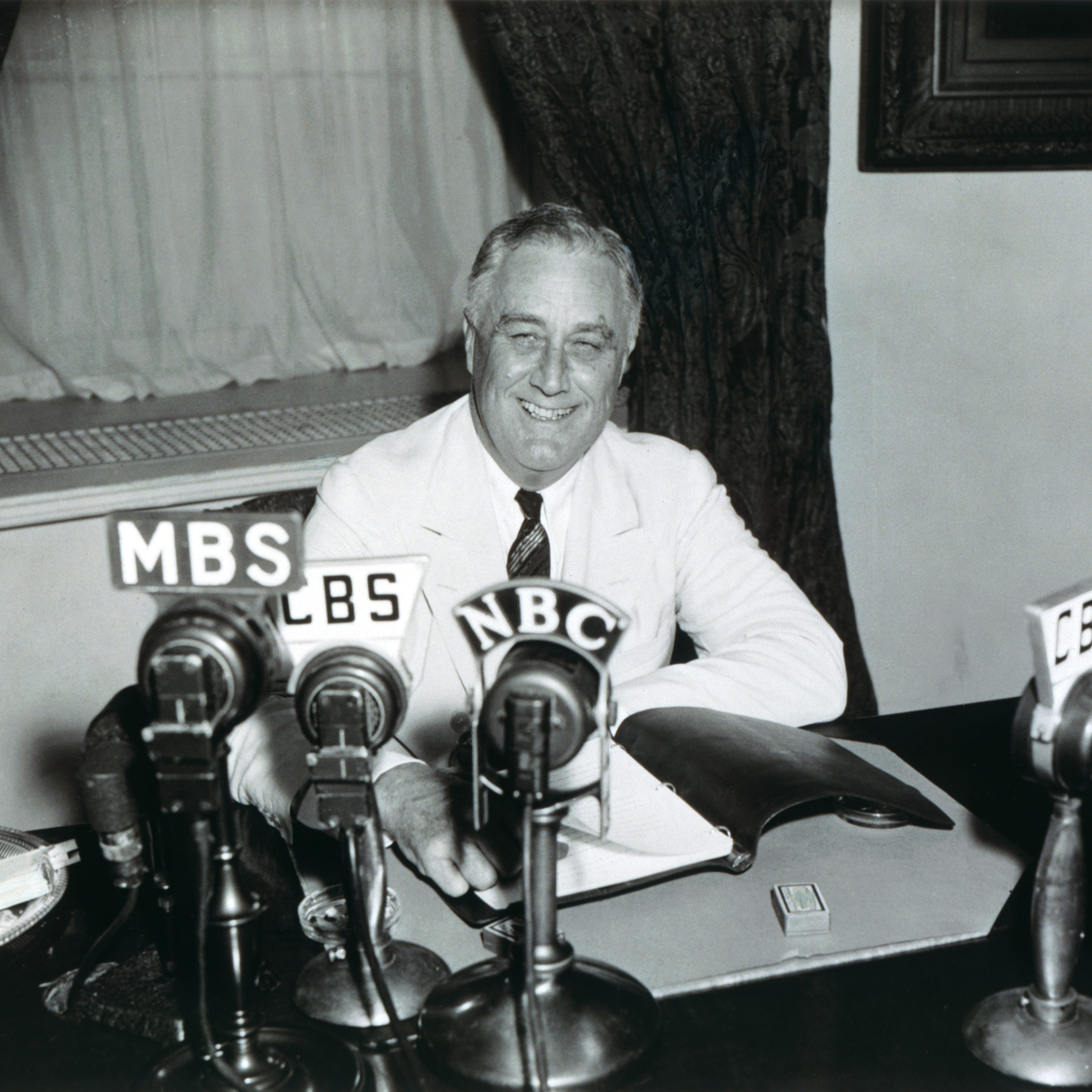 In this black and white photograph by Harris and Ewing, President Franklin D. Roosevelt delivers his 13th Fireside chat describing the accomplishments of the 75th Congress, progress that has been made relating to the Great Depression, and the upcoming 1938 elections.