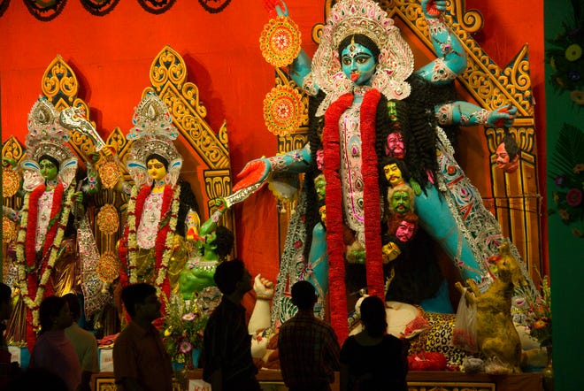 People admire a massive statue of the Hindu goddess Kali in a large neighborhood shrine (pandal) in the New Market Square for the Kali Puja religious festival. In Kolkata, Kali Puja coincides with Diwali, the Festival of Light. Kali, a black incarnation of the Hindu deity Shakti, is the patron god of Kolkata.