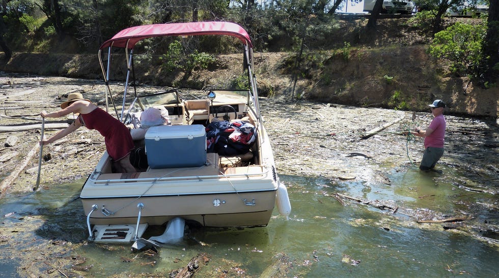 A couple push their boat through debris near a launch on Lake Shasta on Monday, May 15, 2023.