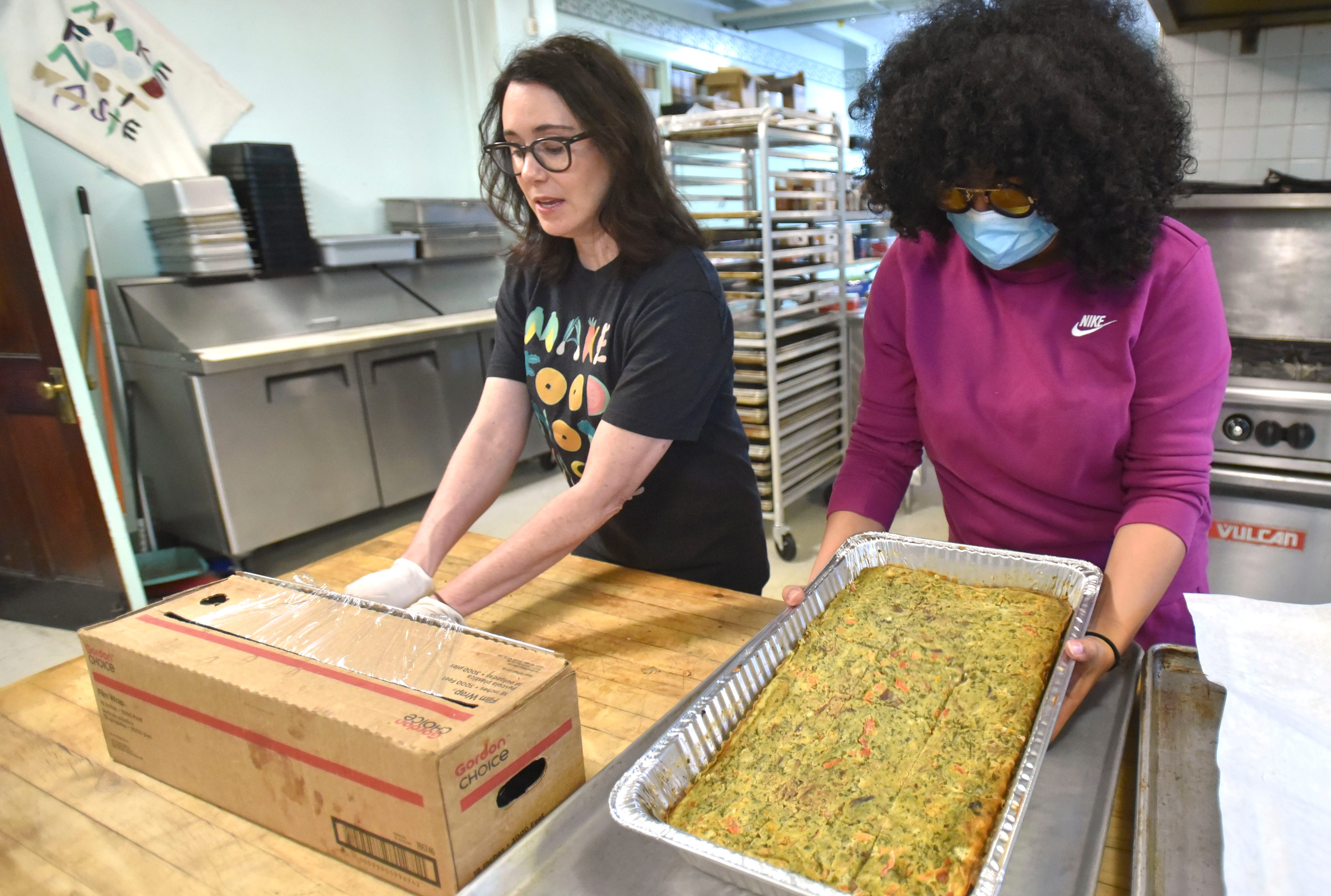 Make Food Not Waste Executive Director Danielle Todd, left, wraps frittatas as Brittany Peeler, community engagement director brings more food in the kitchen basement of the Jefferson Avenue Presbyterian Church before food distribution begins.