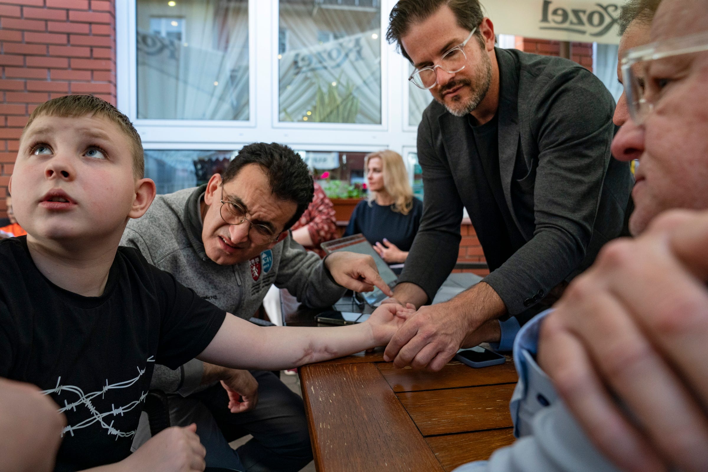 Artem Sokolov, 11, of Kharkiv, Ukraine, left, who was injured in a cluster bomb blast within the last year that left him in a coma for three months and with severe nerve damage in his left arm, gets screened for surgery at a hotel in Leczna, Poland on Sunday, May 14, 2023 by Dr. Gennadiy Fuzaylov, a pediatric anesthesiologist at Massachusetts General Hospital and founder of Doctors Collaborating to Help Children and Dr. Shawn Diamond, a plastic surgeon with Texas Tech Physicians of El Paso and Dr. David Brown a plastic surgeon from the University of Michigan.