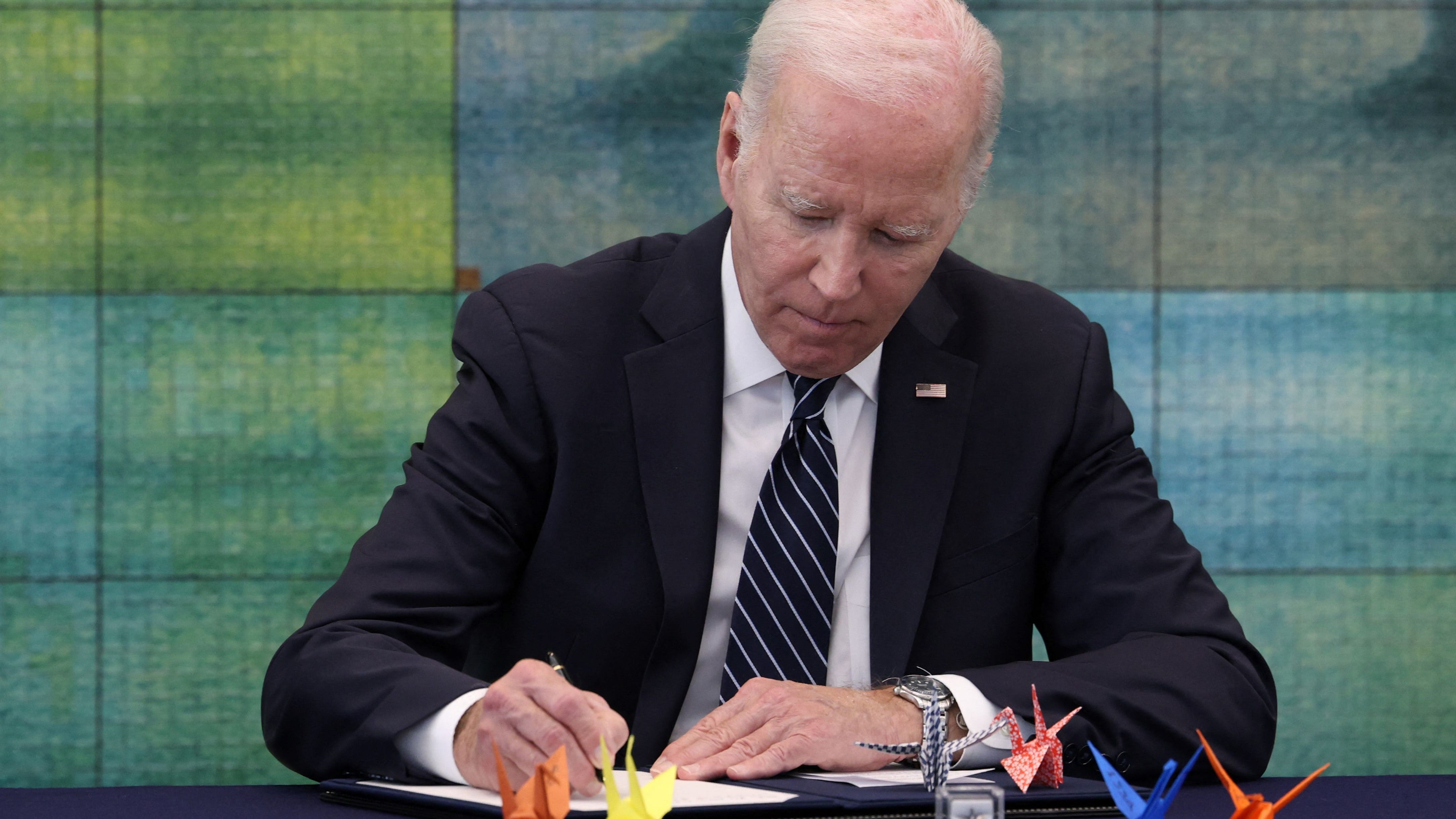 This handout photo taken and released by the Ministry of Foreign Affairs of Japan shows US President Joe Biden signing the guest book as he visits the Peace Memorial Park as part of the G7 Leaders' Summit in Hiroshima on May 19, 2023.