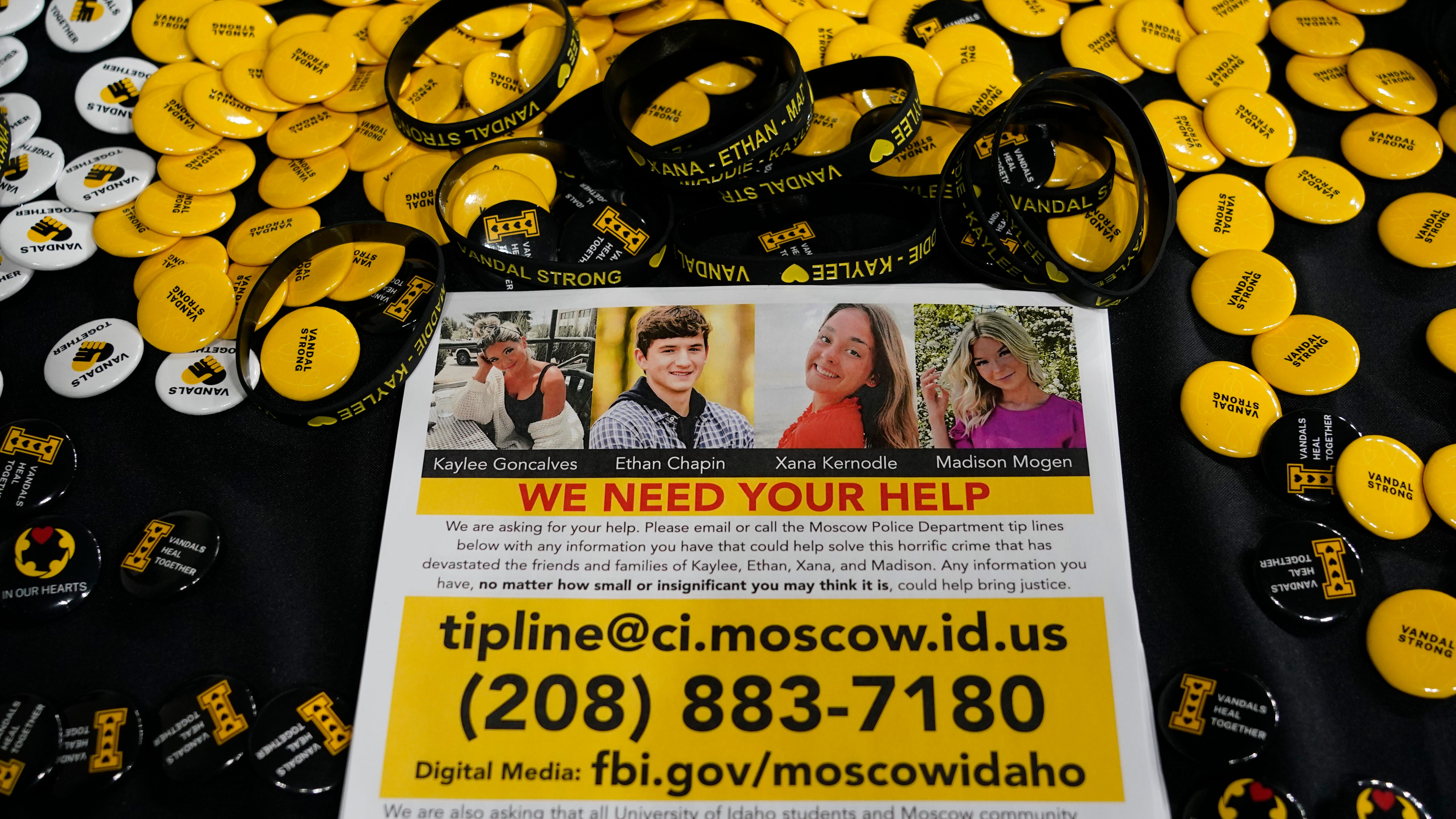A flyer seeking information about the killings of four University of Idaho students who were found dead is displayed on a table along with buttons and bracelets on Nov. 30, 2022, during a vigil in memory of the victims in Moscow, Idaho.
