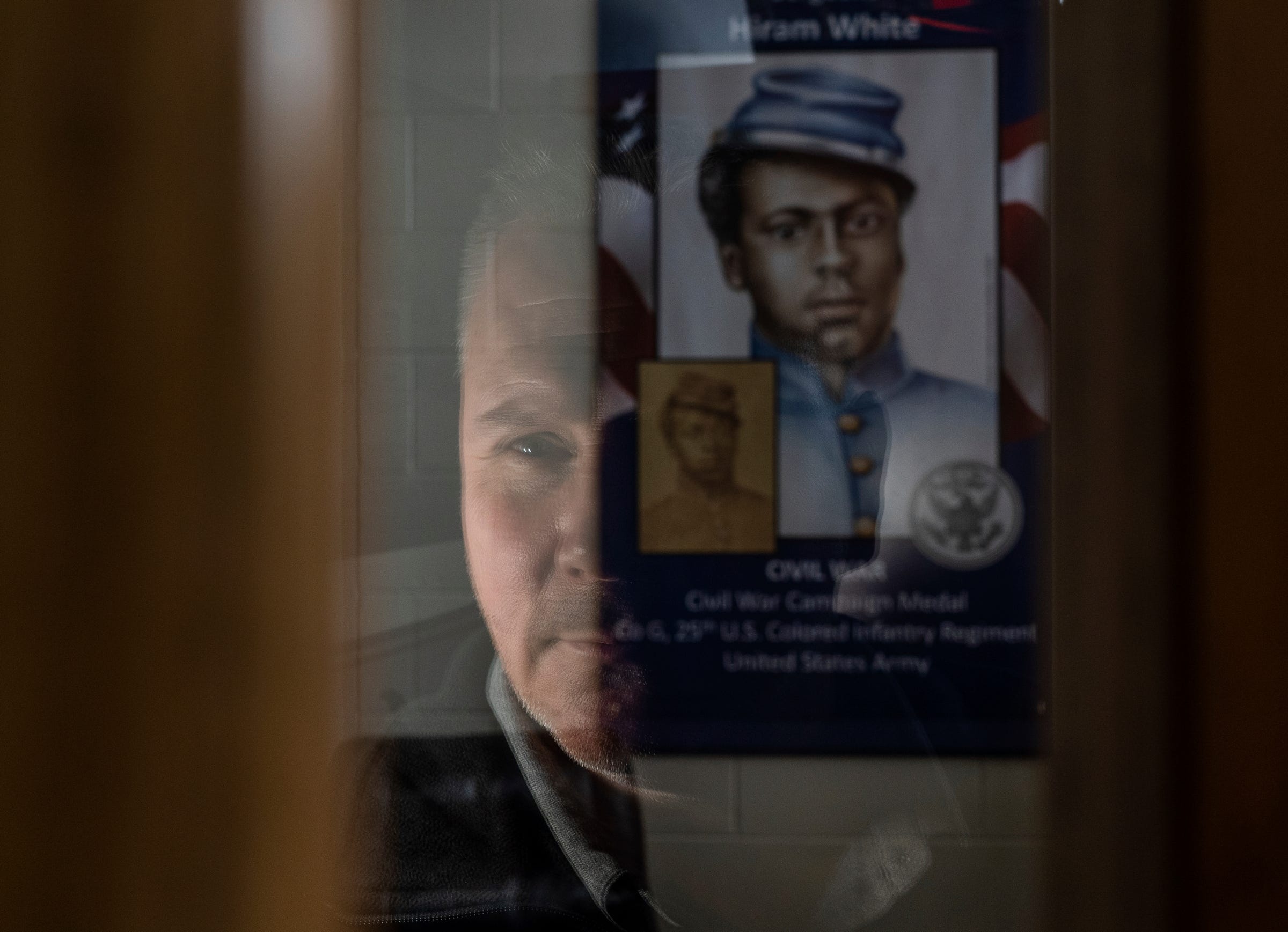 Joe Battisfore, director of the Houghton County Veterans Service Office, sits in his office at the Houghton County Memorial Airport on Sunday, April 23, 2023. In the background is a banner commemorating Sgt. Hiram White, a Civil War soldier whose unmarked grave got a headstone last year thanks to Battisfore's efforts. 