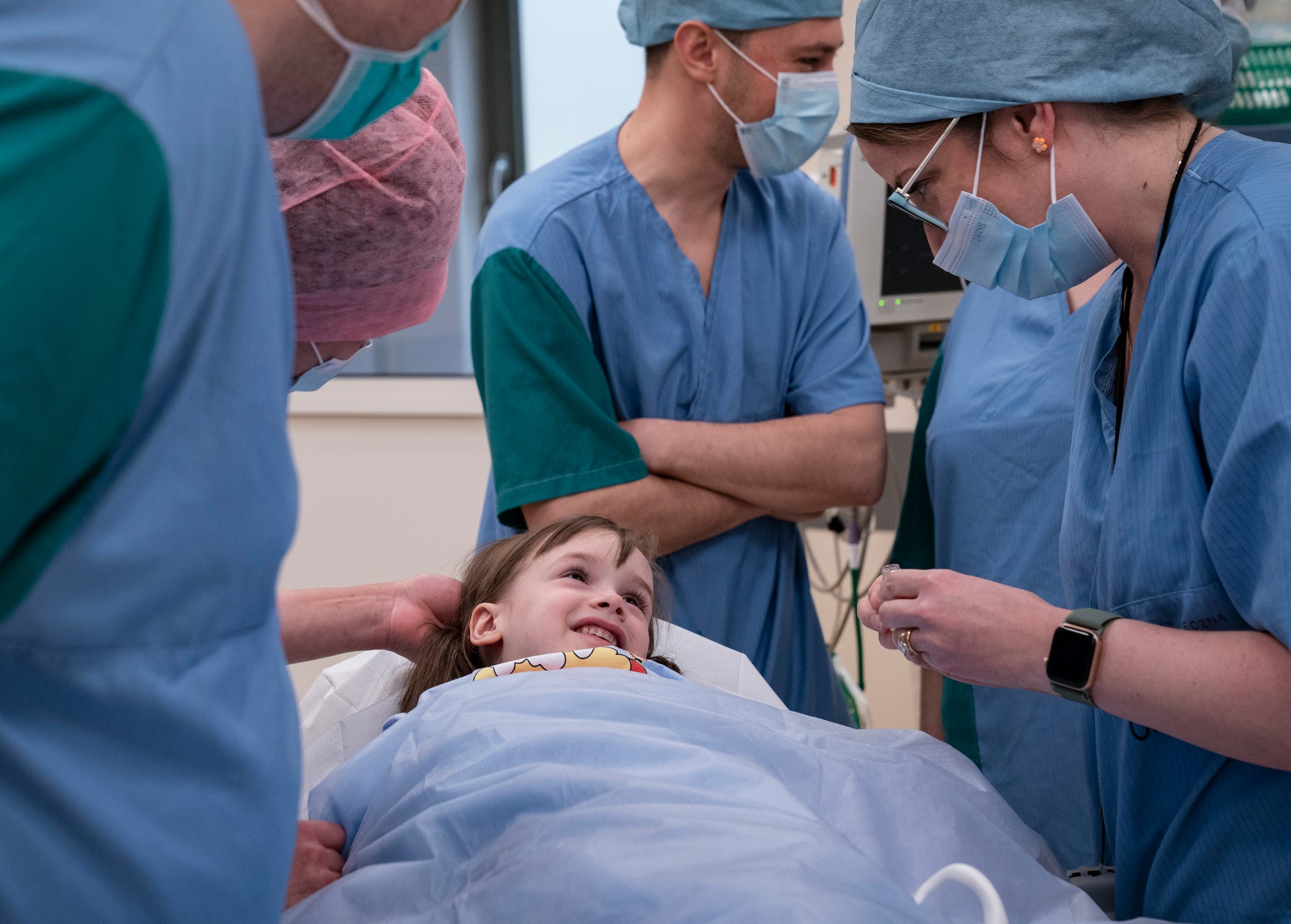 Evheniia Ukhvatova, 6, of Dnipro, Ukraine, locks eyes and smiles with Whitney Roberts, a certified nurse anesthetist from Boston Children’s Hospital before she has surgery to repair burn scars on the back of her legs and feet on Monday, May 15, 2023 at the Independent Public Health Care Facility in  Leczna, Poland. Ukhvatova sustained her burns in a house fire in September 2020.