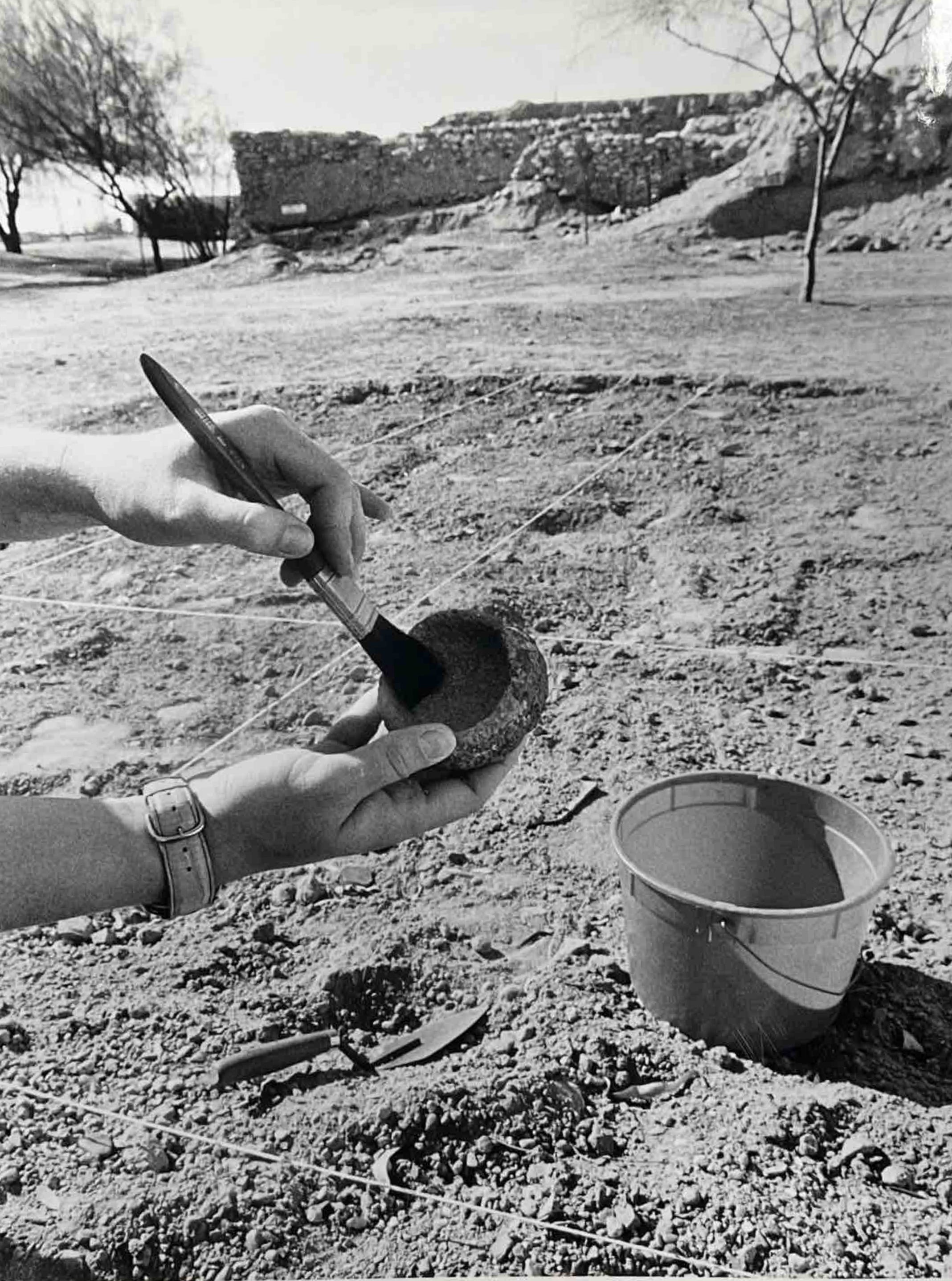A worker dusts an artifact found at Pueblo Grande, now called S'edav Va'ak, in December 1988.