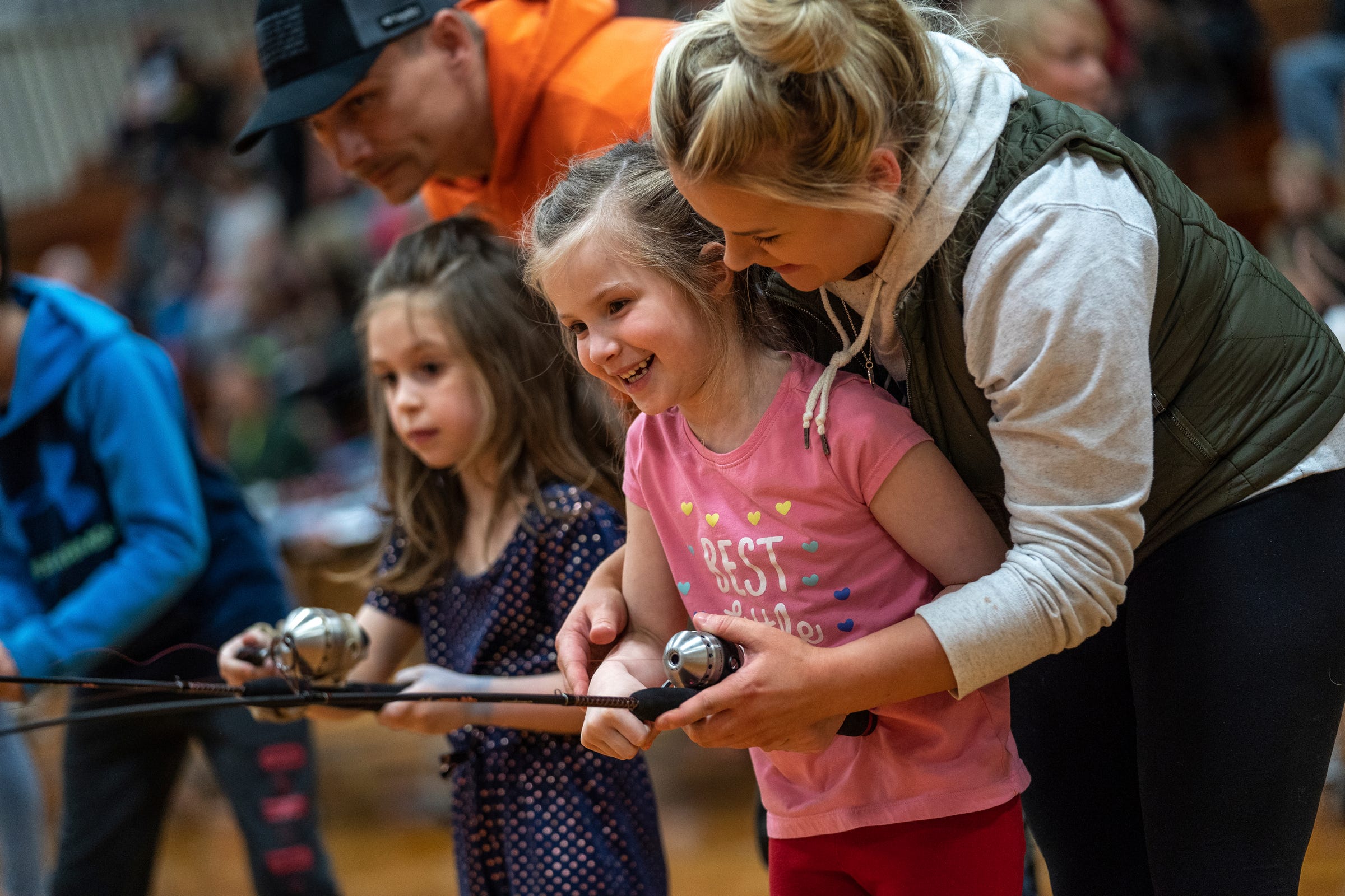 Emily Schummer, right, of Newberry helps her stepdaughter Avery Schultz cast a line while playing a magnetic fishing game inside the gym at Newberry High School during the 65th annual Kids Tackle Party held by the Tahquamenon Sportsmen's Club in Newberry on Saturday, April 22, 2023, in Michigan's Upper Peninsula.
