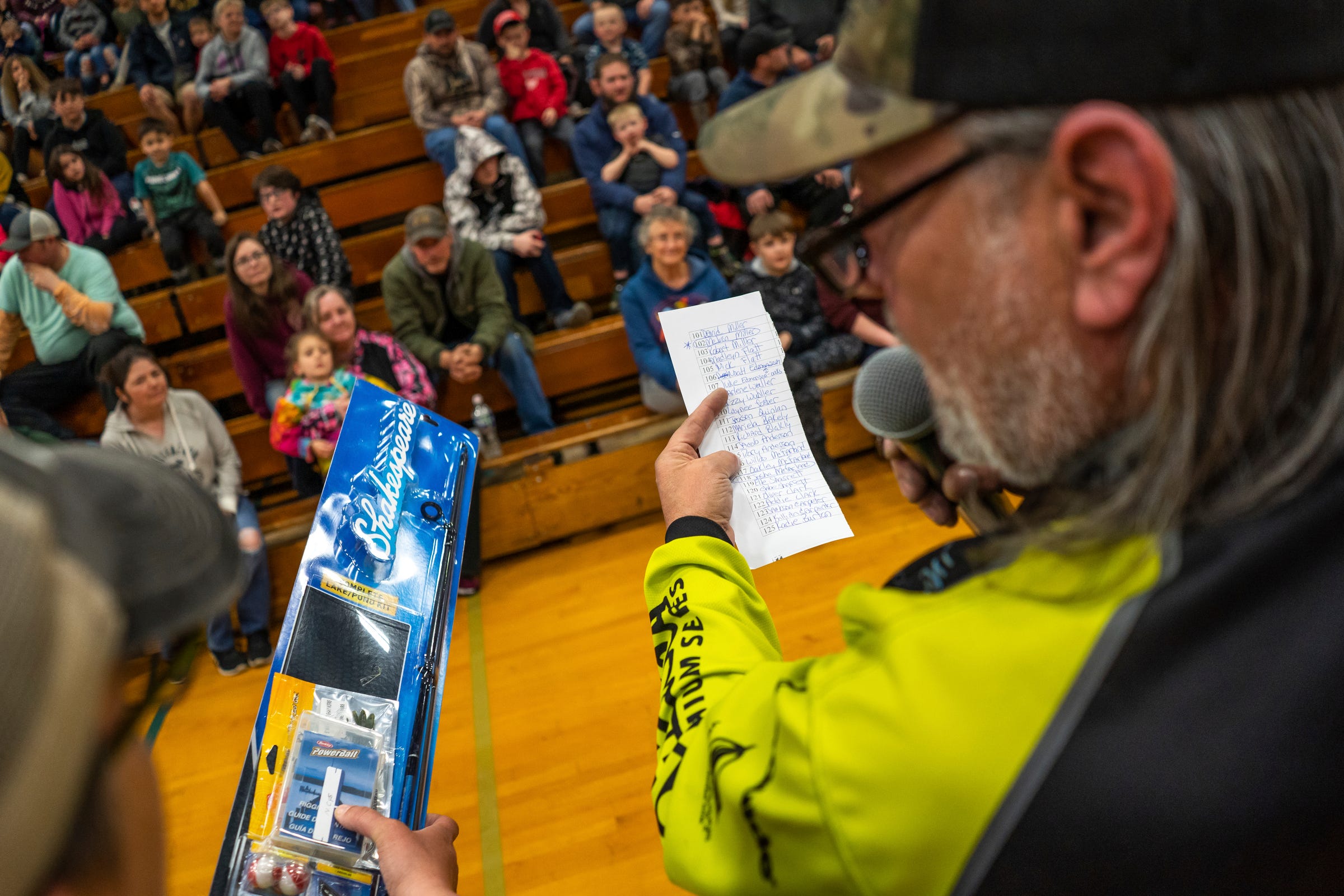 Local DJ and fishing champion Casey Cook, right, of Newberry reads the names of winners to a crowd gathered during the 65th annual Kids Tackle Party held by the Tahquamenon Sportsmen's Club at Newberry High School in Newberry on Saturday, April 22, 2023, in Michigan's Upper Peninsula.