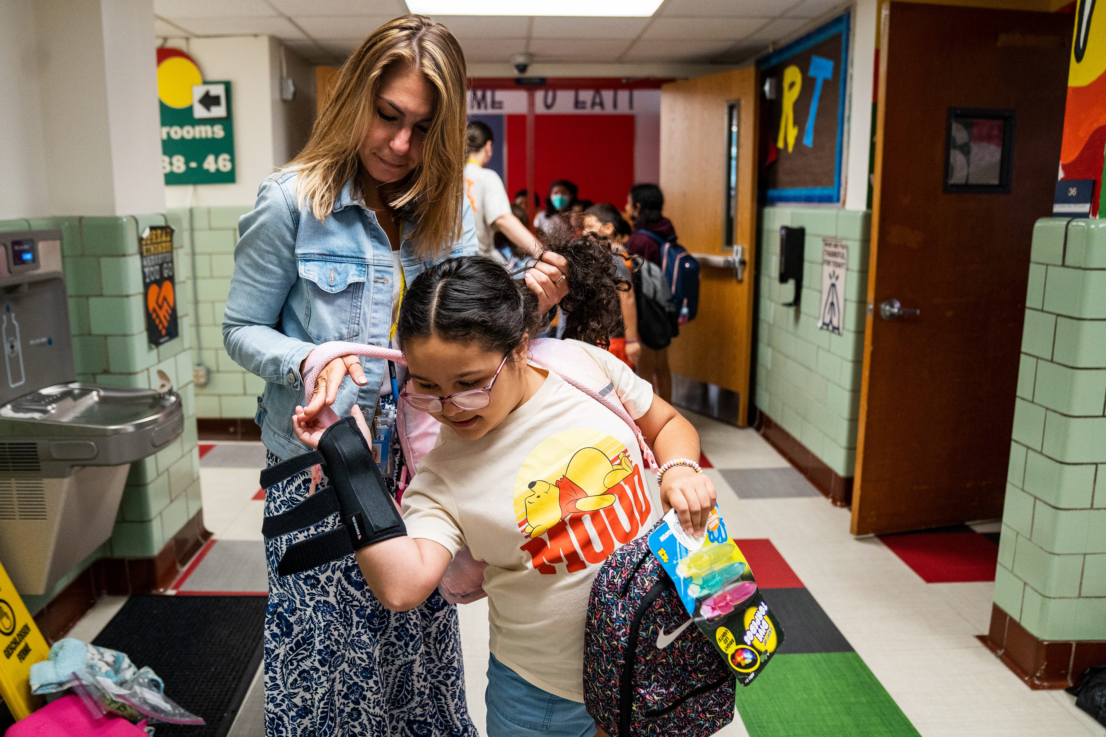 Ashley Soto, a third grader at Cora Kelly Elementary in Alexandria, Va., gets help with her backpack from teacher Daisy Andonyadis.