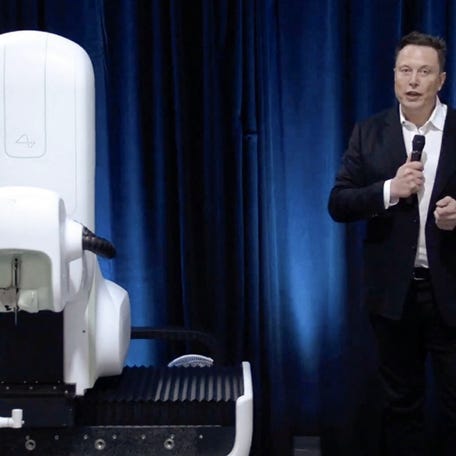 Elon Musk stands next to the Neuralink surgical robot in this video grab from an online presentation on August 28, 2020. Elon Musk's start-up Neuralink on May 25, 2023 said it has gotten approval from US regulators to test its brain implants in people.
