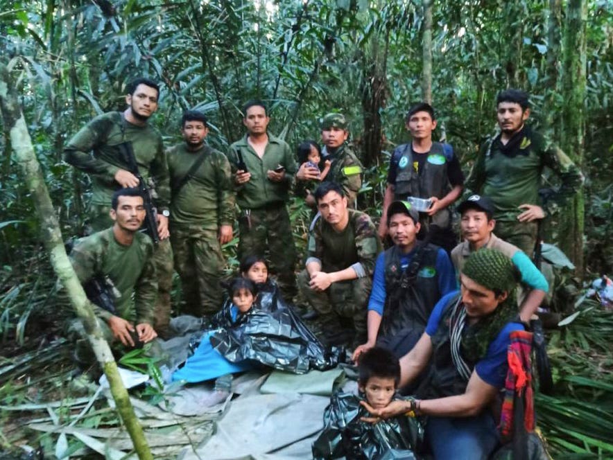 In this photo released by Colombia's Armed Forces Press Office, soldiers and Indigenous men pose for a photo with the four Indigenous brothers who were missing after a deadly plane crash, in the Solano jungle, Caqueta state, Colombia, Friday, June 9, 2023. (Colombia's Armed Force Press Office via AP)