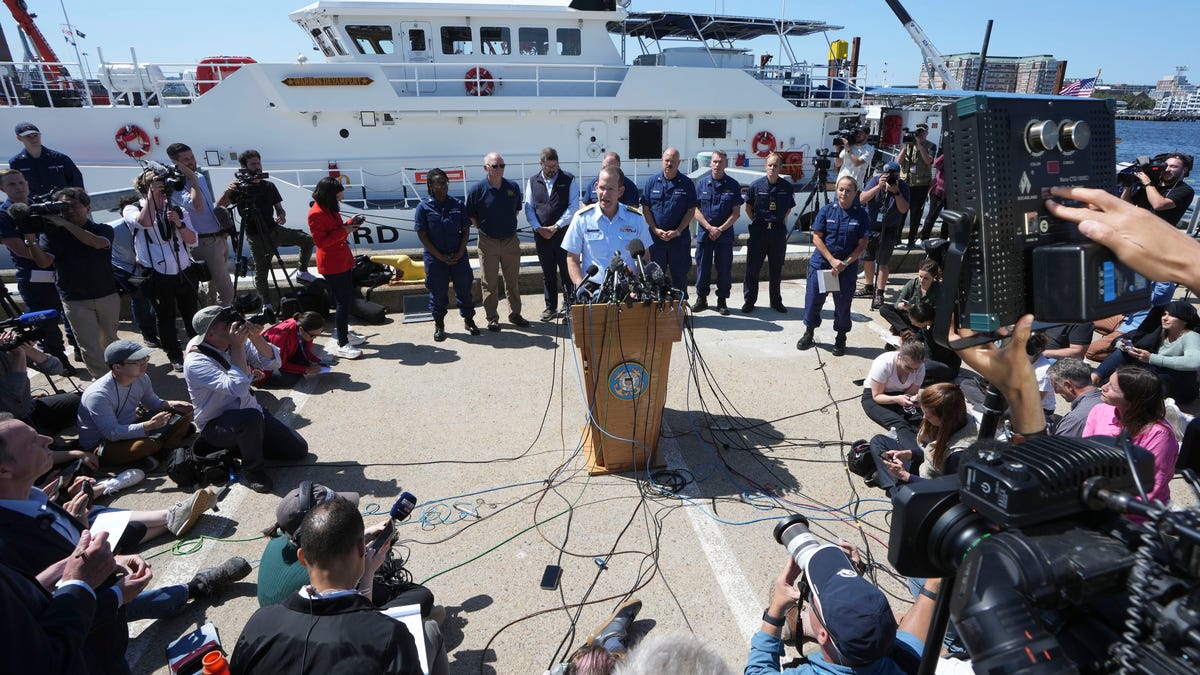 U.S. Coast Guard Rear Adm. John Mauger, commander of the First Coast Guard District, center at microphone, talks to the media Thursday, June 22, 2023, at Coast Guard Base Boston, in Boston. The U.S. Coast Guard says the missing submersible imploded near the wreckage of the Titanic, killing all five people on board. Coast Guard officials said during the news conference that they've notified the families of the crew of the Titan, which has been missing   for several days.